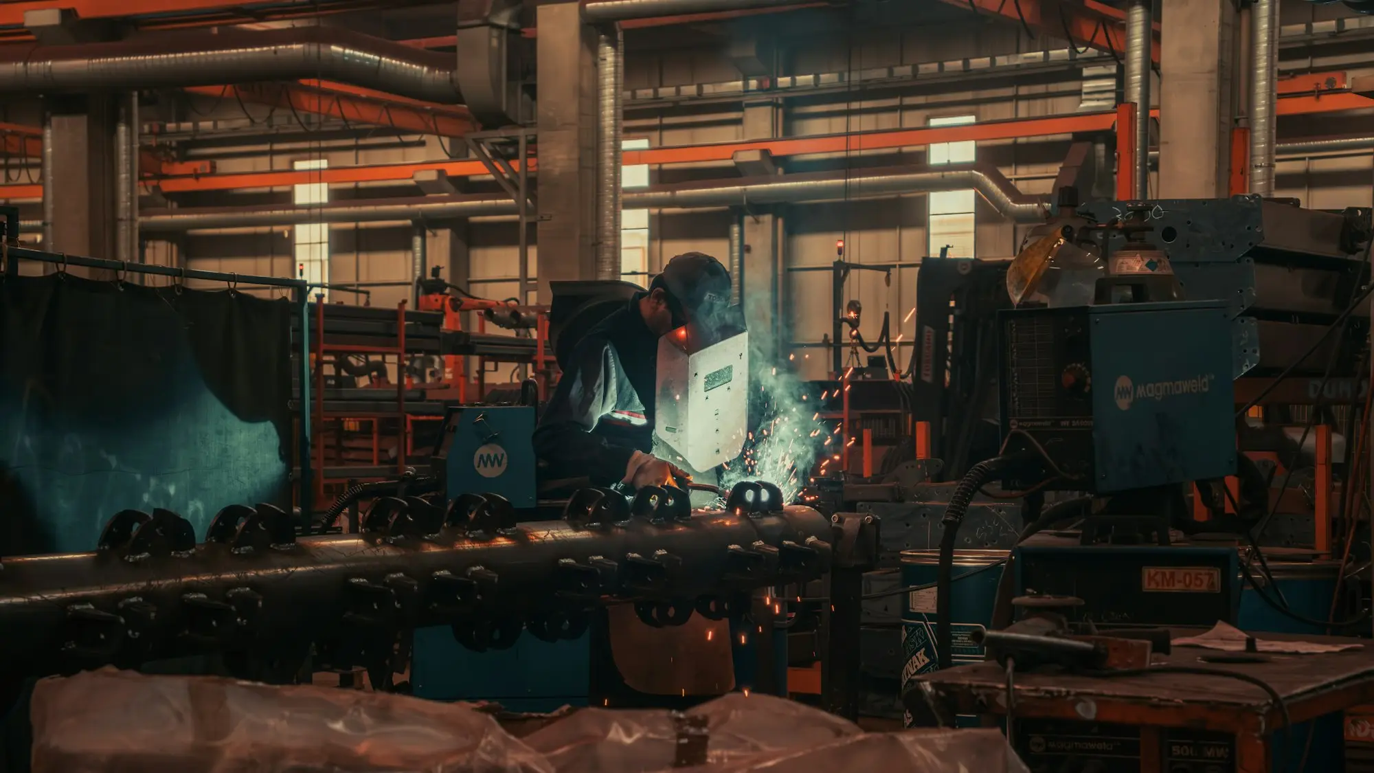 Skilled welder working on steel pipe in a fabrication workshop, the kind of specialist an engineering SME depends on